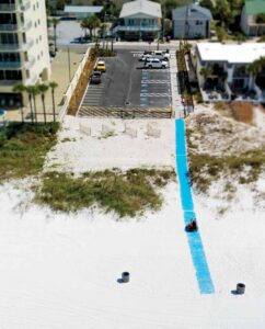 An aerial view of Edward F. Hickey, Jr. Park showing a parking lot with ADA-accessible spaces and a blue mobility mat leading to the white sandy beach.